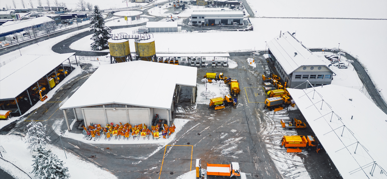 Aerial view of a worksite covered in snow with workers preparing for winter weather,